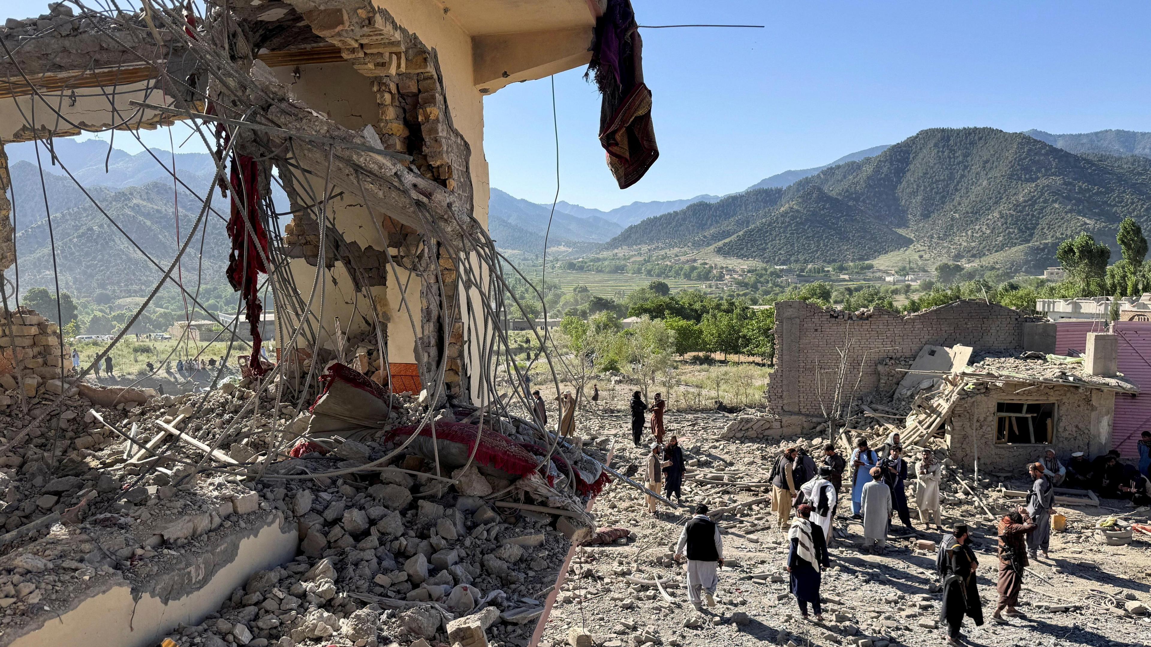People inspect a damaged house in Mandokhail village, Paktia province