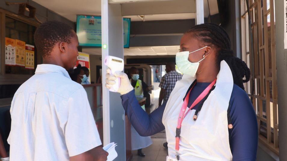 Medical worker checks temperature of traveller at Kenyan border crossing
